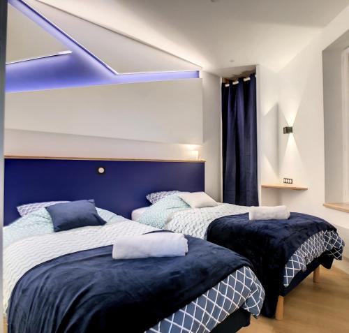 two beds in a bedroom with a blue headboard at Escalier 16 - 30 m plage du Sillon - Proche Intra in Saint Malo