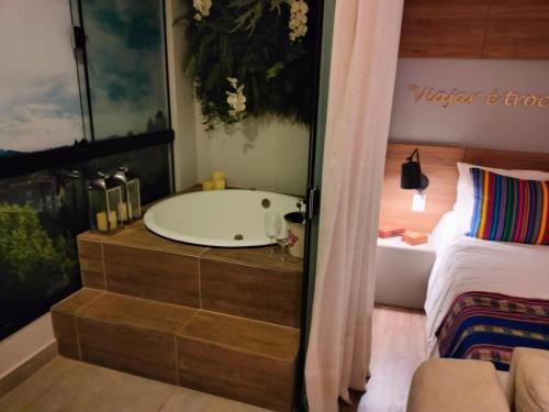 La salle de bains est pourvue d'une baignoire à côté d'un lit. dans l'établissement Wanderlust Experience Hotel, à Campos do Jordão