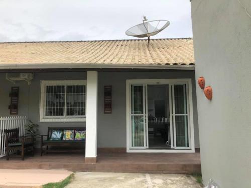 a porch of a house with a bench and a satellite at Bombinhas Brasil Residence Tourist Home no Centro de Bombinhas in Bombinhas