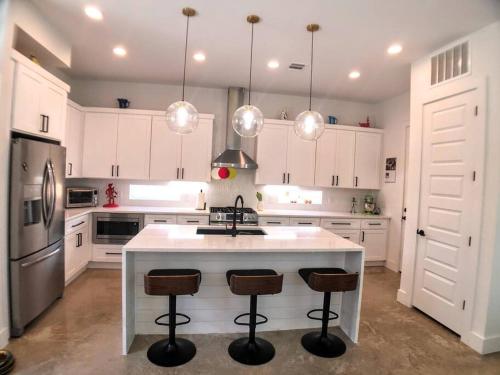 a kitchen with white cabinets and a kitchen island with bar stools at East Austintacious: walkable airy arty 4 bedroom 3 1/2 bath in Austin