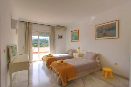 a bedroom with two beds and a table and a window at 1175 villa el paraiso in Estepona