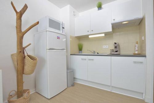 une cuisine avec des armoires blanches et un réfrigérateur blanc dans l'établissement Appartement cosy 4 personnes, au Grau-du-Roi