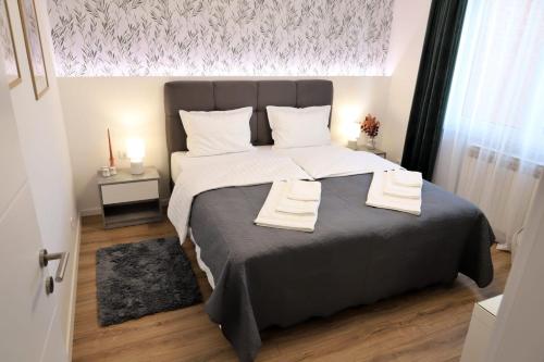 een slaapkamer met een groot bed en 2 handdoeken bij Apartman Nila in Vukovar