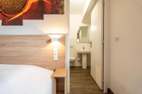 um quarto com uma cama e uma casa de banho com um lavatório em My KB Hôtel Montélimar em Saulce-sur-Rhône