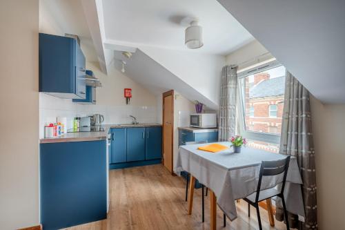 a kitchen with blue cabinets and a table with chairs at Apartment in city centre, close to bars and resturants in Belfast