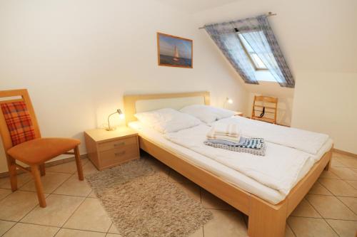 1 dormitorio con 1 cama con silla y ventana en Ferienwohnung Strand25, en Trassenheide
