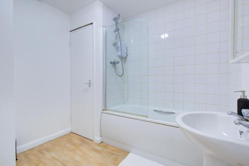 a white bathroom with a shower and a sink at Town Centre Apartment in Croydon