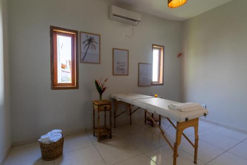 a white bathroom with a sink and a window at Villa Alexandre Pousada - Trancoso in Trancoso