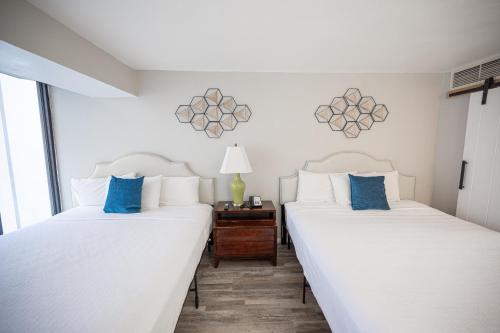 two beds in a room with white sheets and blue pillows at Stay Together Suites - Stylish Condominium On The Strip Sleeps 12 - NO RESORT FEE in Las Vegas