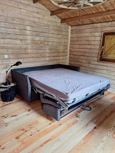 a bed in a room with a wooden wall at Le CHALET in Pressins