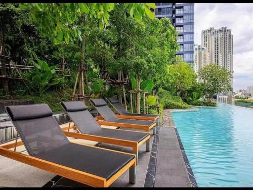 a row of lounge chairs next to a swimming pool at Free airport pick-up/Aerial rainforest/Near subway line/Train night market/Central rama 9/Super high-rise luxury apartment/Night view/RCA in Bangkok
