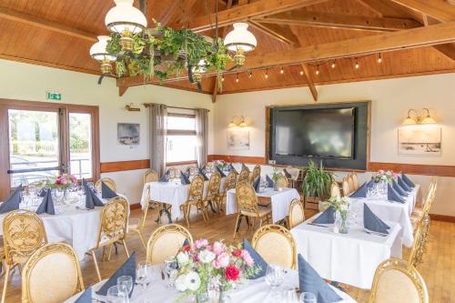 um salão de banquetes com mesas e cadeiras e uma televisão de ecrã plano em La Ferme Du Grand Air em Fiennes