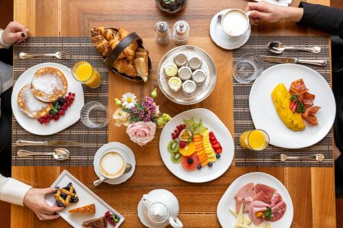 フィレンツェにあるPalazzo Firenze by Baglioni Hotels & Resortsの食べ物の皿が置かれた木製のテーブル