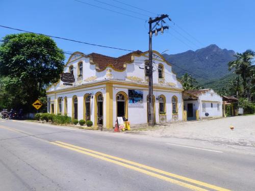 un edificio amarillo y blanco al lado de una calle en Pousada e Restaurante Dona Siroba, en Morretes