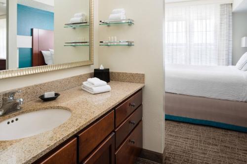 a bathroom with a sink and a bed and a mirror at Residence Inn by Marriott Cypress Los Alamitos in Los Alamitos