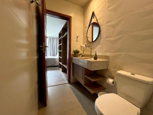 a bathroom with a toilet and a sink and a mirror at Luxuoso Apto na Villa de BG. in Marau