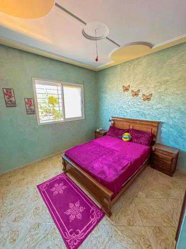 a bedroom with a bed with purple sheets and a window at Soofhouse in Fez