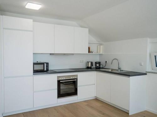 a white kitchen with white cabinets and a sink at Ferienwohnung Weissach in Weissach
