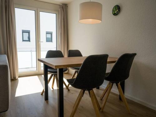 a dining room table with four chairs and a large window at Ferienwohnung Weissach in Weissach