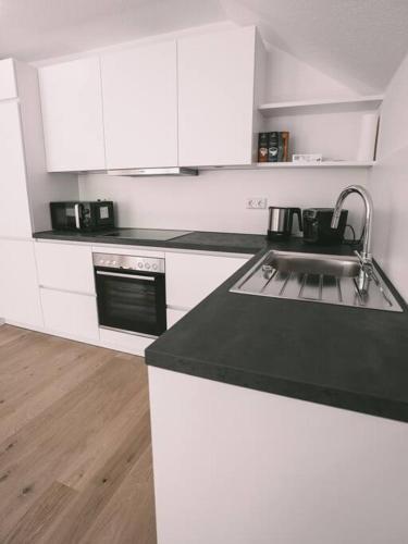 a kitchen with white cabinets and a black counter top at Ferienwohnung Weissach in Weissach