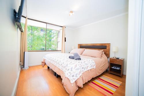a bedroom with a bed and a large window at Full departamento, Metro Manquehue, Las Condes in Santiago