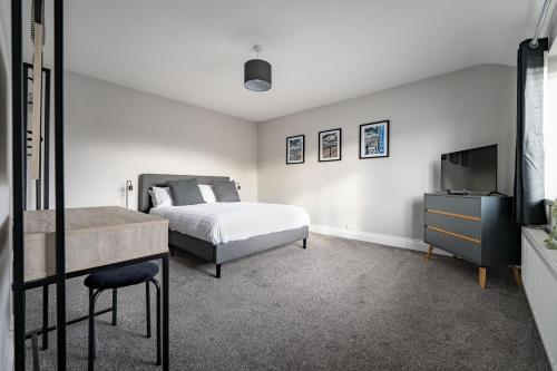 a bedroom with a bed and a dresser and a television at William Street Apartment in Cleethorpes