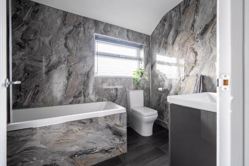 a bathroom with a toilet and a tub and a sink at William Street Apartment in Cleethorpes