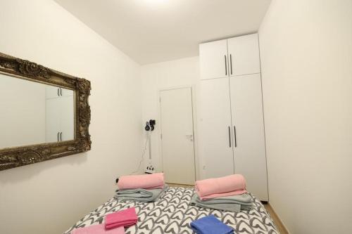 a bedroom with a bed with pink and blue pillows and a mirror at Apartman MRL Cavic in Banja Luka