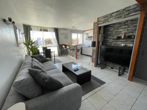 un salon avec un canapé et une télévision à écran plat dans l'établissement Appartement Port Marianne Montpellier, à Montpellier