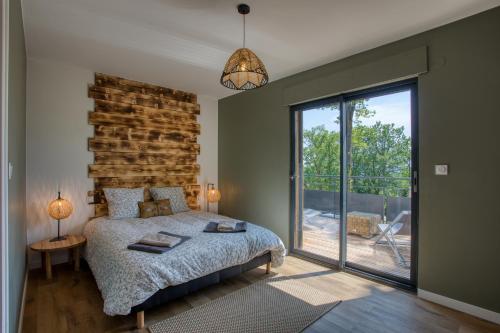 een slaapkamer met een bed en een groot raam bij Le domaine du Pech Eternel in Sarlat-la-Canéda