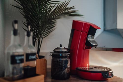 a red coffee maker sitting on a table next to a bottle at Fewostaeps- Moderne Unterkunft, zentrumsnah in Plauen