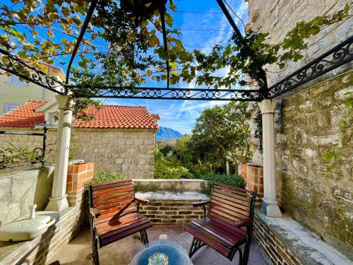 two benches sitting on a patio with a fountain at Old town house with private garden in Budva