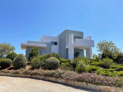 a house with a garden in front of it at Helios a modern large villa with private pool set in a quiet location in Stavros