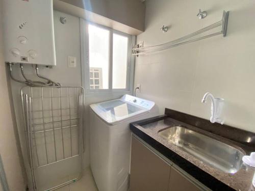 uma cozinha branca com um lavatório e uma janela em Apartamento com vista ampla para o mar. em Governador Celso Ramos