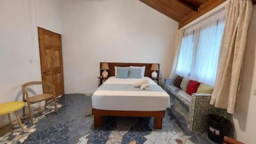 a bedroom with a bed and a window and a couch at Casa THIREMA Tortuguero in Tortuguero