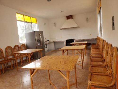 cocina con mesas, sillas y nevera en Peña de Bernal Rancho La Trinidad, 