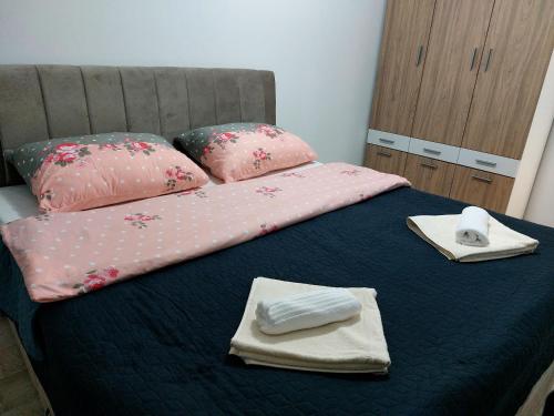 Una cama con sábanas rosas y toallas. en Apartman-Stan, en Bugojno