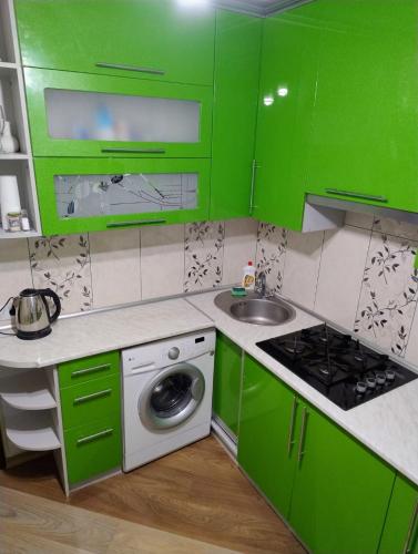 cocina verde con fregadero y lavadora en Хорошая однокомнатная квартира в центре города en Shostka