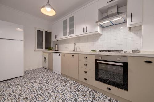 a kitchen with white cabinets and a tile floor at Gurel Garden House in Kucukkuyu