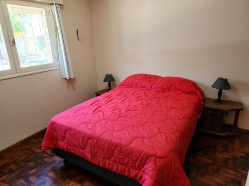 a bedroom with a bed with a red comforter and a window at DEPARTAMENTO BARCALA PLENO CENTRO DE MENDOZA in Mendoza