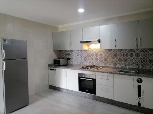 a kitchen with white cabinets and a stainless steel refrigerator at Apartment chakira family only in Tangier