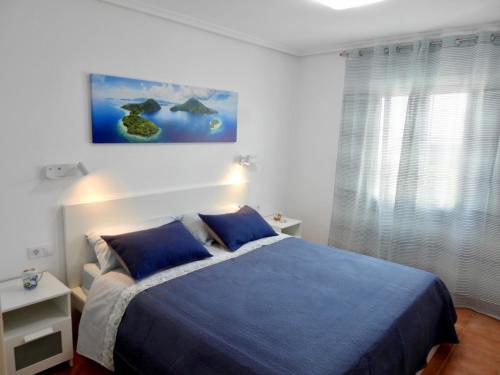 a bedroom with a blue bed and a painting on the wall at Casa Mirasol, WIFI y NETFLIX free in Playa Honda