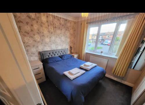 a bedroom with a blue bed and a window at Cosy 2 bed house in the heart of leyland in Leyland