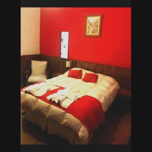a bedroom with a large bed with a red wall at Apart Franchino in Mina Clavero