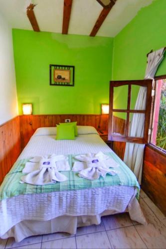 Un dormitorio verde con una cama con toallas. en Apart Franchino en Mina Clavero