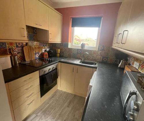 a kitchen with white cabinets and a sink and a window at Waterside Villa in Corton