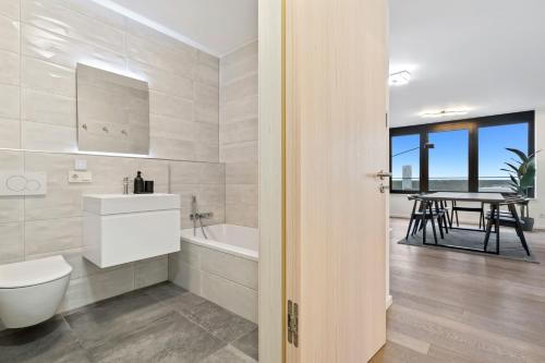 La salle de bains est pourvue de toilettes, d'une baignoire et d'une table. dans l'établissement Modern 2BR Apartment with Pool & City Views, à Luxembourg