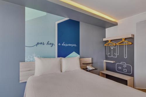 1 dormitorio con cama y pared azul en One Irapuato, en Irapuato