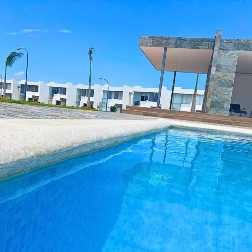 a blue swimming pool in front of a building at Casa Familiar a Pasos del Mar Playa y Felicidad in Manta
