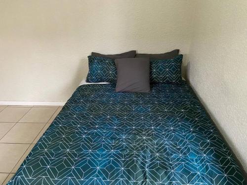 Cama en habitación con colcha y almohadas azules en Comfortably gel with the locals!, en Ciudad del Cabo